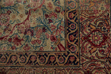 Cochineal red floral blossoms, aqua teal branches, and scrolling navy border on this antique Kerman rug.