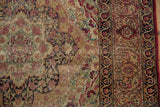 Persian Kerman rug's dusty gold field, cochineal red roses, and ornate navy border.