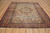 Ornate floral border of the antique Kerman rug featuring cochineal red, navy blue, and ivory, with fringe.