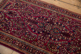 Delicate floral vines and sprays in navy and ivory across a cherry red vintage Sarouk rug.
