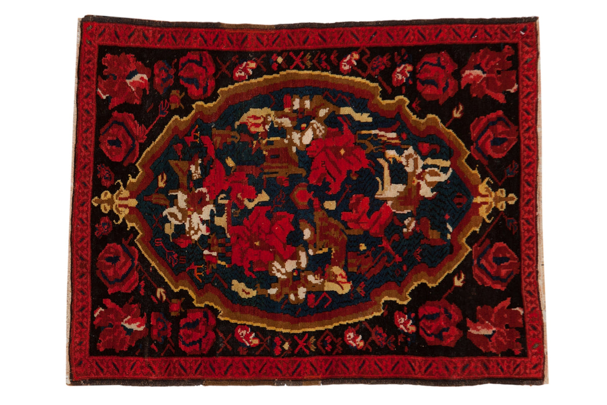 Vintage Karabagh rug featuring an oversized medallion with red roses and vinery on a dark field.