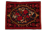 Vintage Karabagh rug featuring an oversized medallion with red roses and vinery on a dark field.