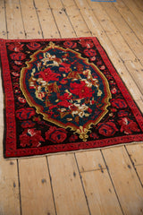 Vintage Karabagh rug with an oversized rose medallion and red border shown at a full-length angle.