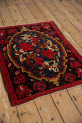 Vintage Armenian Karabagh rug with a floral teal medallion and black cherry red roses on a dark field.