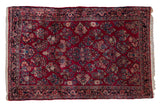 Vintage German Sarouk rug with allover floral bouquets on a cherry red field with a dark navy border.