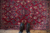 A view from above showing the texture and dense floral pattern of a vintage Sarouk rug underfoot.