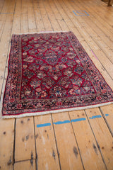 Angled view of a vintage German Sarouk rug highlighting the traditional floral sprays on a red field.