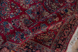 A folded corner of a vintage German Sarouk rug reveals its plush texture and finely knotted floral sprays.