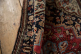 Finely hand-knotted pile of an antique Farahan Sarouk rug, displaying intricate vinery in navy, ruby, and ivory.