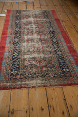 Angled view of an antique Serab runner showing a time-worn field against navy and cherry red borders.