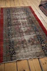 Angled perspective on an antique Serab runner showing worn pile and exposed foundation.