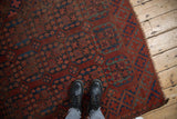 Feet on vintage Ersari rug, highlighting chestnut and navy blossom guls and worn edges.