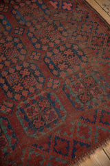 Ersari rug detail: chestnut and indigo blossom guls, visible pile wear, and frayed end.