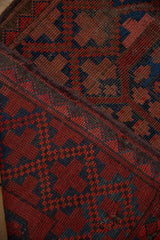 Close-up of vintage Ersari rug showing geometric guls, mostly even pile wear, and tattered edge.