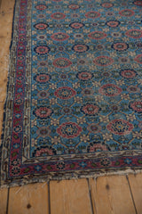 Tattered edge of Lilihan rug, with visible foundation, raspberry red border, and sky blue Veramin field.