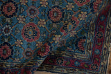 Curled pile of vintage Lilihan rug, showing sky blue field, raspberry red, and vinery lattice.