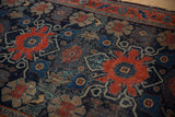 Antique Senneh rug's intricate navy field, cherry red floral vinery, and authentic worn texture.