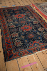 Antique Senneh rug's intricate floral vinery on navy blue, with a softly tattered end.