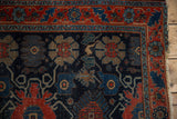 Antique Senneh rug's tattered corner, with red border and navy field's intricate floral vinery.