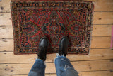 Classic Sarouk style Lilihan rug mat with brick red field, floral medallion, and tattered ends.