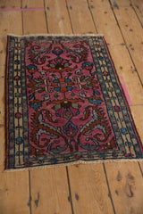 Angled view of a vintage Borchalou rug with bold floral arabesques on a rich fuchsia field.
