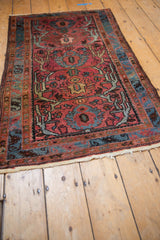 Vintage Mehriban rug's dusty raspberry floral palmette, scrolled vines, and serpent border.