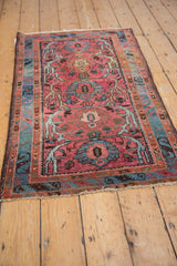 Dusty raspberry floral palmette with dramatic scrolled vines and blue laurel motif.