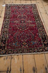 Close-up of vintage Lilihan rug's raspberry red field, intricate floral sprays, and navy border.