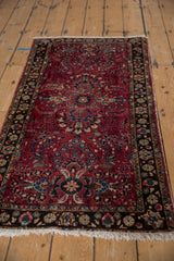 Vintage Lilihan rug's raspberry red field, intricate blossomed floral sprays, and dark navy border.