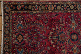 Lilihan rug corner detail: raspberry red field, scrolled floral navy border, and fringe.