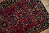 Raspberry red field intricate with blossomed floral sprays, next to a charcoal navy border.