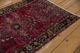 Charcoal navy blue border with scrolled leaves and raspberry red floral field of the Lilihan rug.