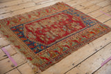 Worn cherry red Anatolian rug showing foundation, with sapphire blue border details.