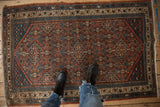 Densely ornamented vintage Hamadan rug with brick red and dusty teal floral blossoms underfoot.
