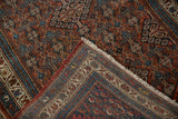 Vintage Hamadan rug corner, showing brick red and teal floral pattern, hand-knotted reverse, and fringe.