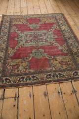 Antique Persian Doroksh rug corner, cochineal red field, palmette spandrel, and meandering vine border.
