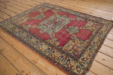 Corner of antique Persian Doroksh rug, with colorful meandering vine border and beige spandrel.