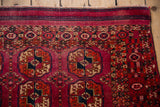Knotted striated end bands and barber pole style borders on a fuchsia and navy Turkmen rug.