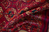 The soft, textured pile of a vintage Turkmen rug, draped to show its fuchsia gul motif.