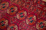Low pile texture and hand-knotted elephant footprint guls on a fuchsia Turkmen rug.