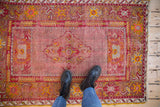 Worn central medallion and cherry red field of a vintage Anatolian rug with dusty gold designs.