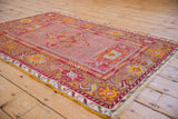 Anatolian rug corner showing red-gold floral border, visible fringe, and wear.