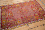 Vintage Anatolian rug corner; cherry red main border, saffron floral motifs, and visible foundation wear.