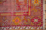 Vintage Anatolian rug corner showing worn pink seeded field, cherry red floral border, and fringe.