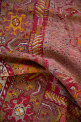 Worn pile of the vintage Anatolian rug, with exposed foundation and cherry red tones.