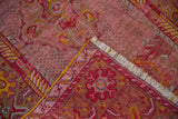 Folded vintage Anatolian rug displaying its worn cherry red pile, visible foundation, white fringe, and yellow selvedge.