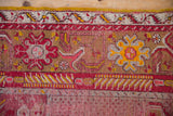 Vintage Anatolian rug's yellow selvage, cherry red borders, dusty gold patterns, and visible foundation wear.