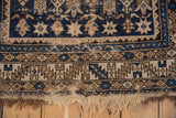 Antique Caucasian rug's serrated leaf border in sapphire blue and beige, showing low pile and worn fringe.