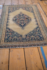 Antique Senneh rug's fringed end showing detailed navy and beige Herati motif on corner spandrel.
