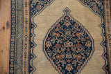Stepped contour Herati medallion motif in navy, coral, and beige on an antique Persian Senneh rug.
